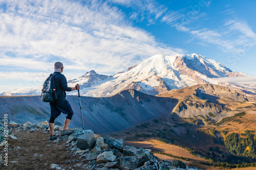 A hiker looking at Mount Rainier with hiking poles in his hand