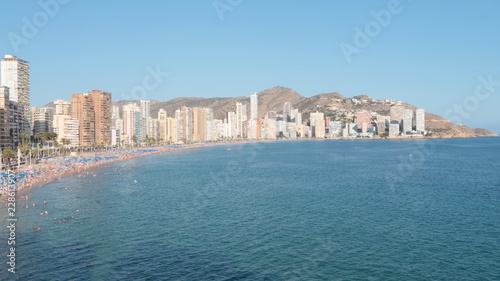 Playa de levante llena de personas en la arena tomando el sol y bañandose en el agua del mar