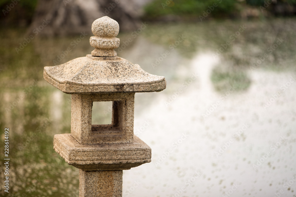 Close up japanese stone lantern in public park. Stone lantern in a Japanese garden on a rainy day. Selective focus on the lantern. Stone lantern in japanese garden . Close up japanese stone lantern in public park. Stone lantern in a Japanese garden on a rainy day. Selective focus on the lantern. Stone lantern in japanese garden .