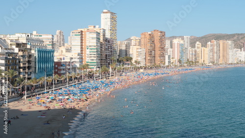 Playa de levante llena de personas en la arena tomando el sol y ba  andose en el agua del mar