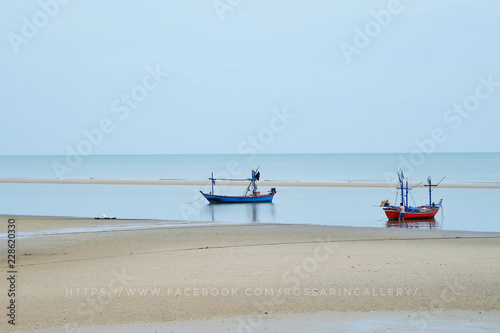 Boat on sand at sea beach in tropical resort on blue sky background. Summer vacation, recreation, travelling concept.