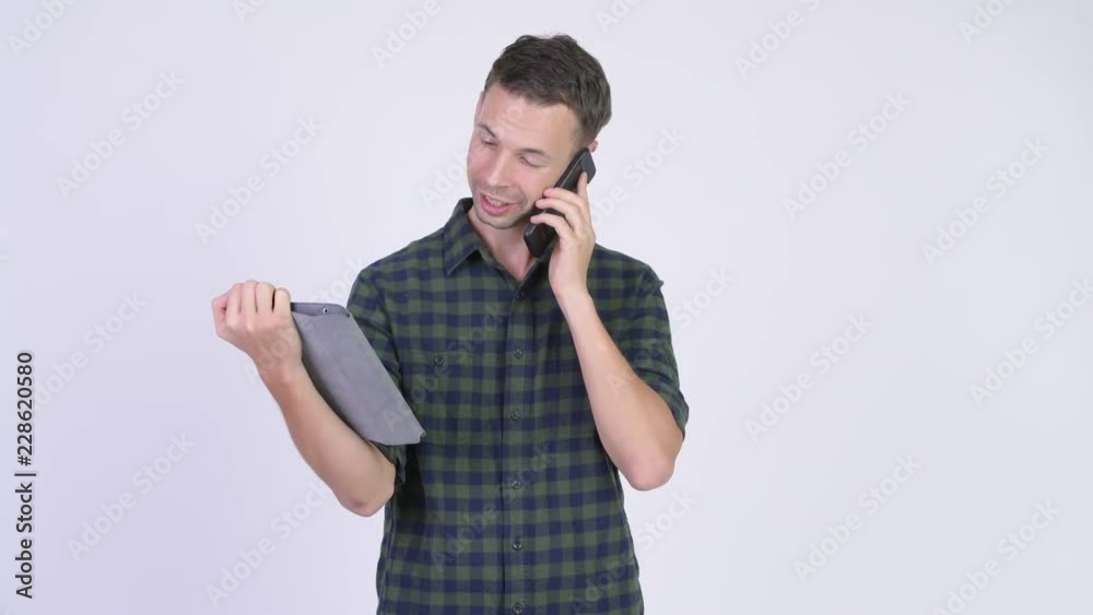 Studio shot of happy hipster man talking on phone and using digital tablet Studio shot of happy hipster man talking on phone and using digital tablet