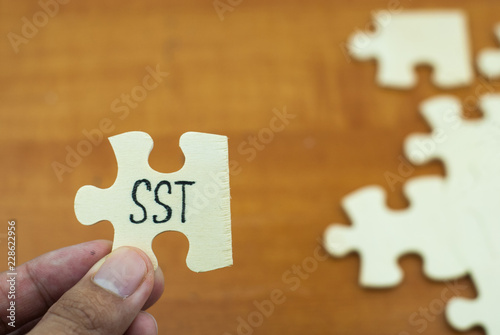 Wooden puzzle with text SST (Sale and services tax). Tax concept.