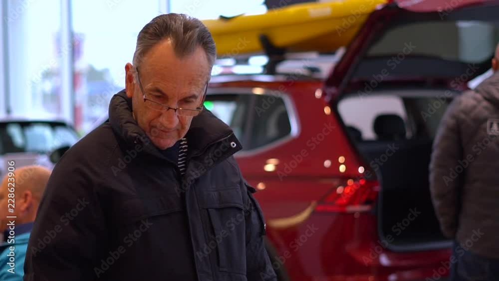 Senior man car shopping looking to buy an automobile inside dealership