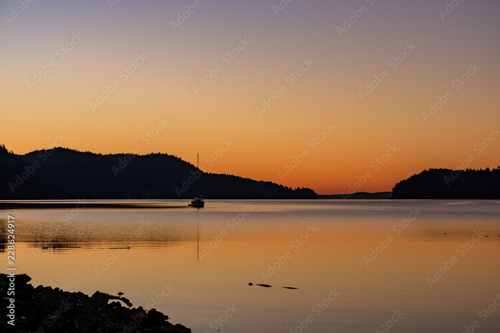 minutes before sunrise over the back of the mountain with glowing orange sky by the water front