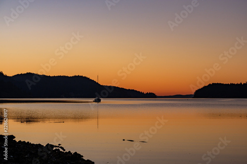 minutes before sunrise over the back of the mountain with glowing orange sky by the water front