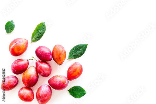 Fototapeta Naklejka Na Ścianę i Meble -  Summer harvest of red plum.  Red plum and leaves pattern on white background top view space for text