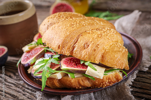 Fresh croissant sandwich with brie cheese arugula and figs. Delicious breakfast. Tasty food.