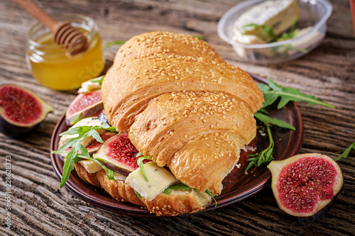 Fresh croissant sandwich with brie cheese arugula and figs. Delicious breakfast. Tasty food.