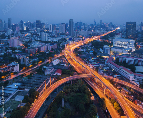 Cars driving on bridge roads shaped curve highways with skyscraper buildings. Aerial view of Expressway Bangna, Klong Toey in structure of architecture concept, Urban city, Bangkok at night, Thailand. photo