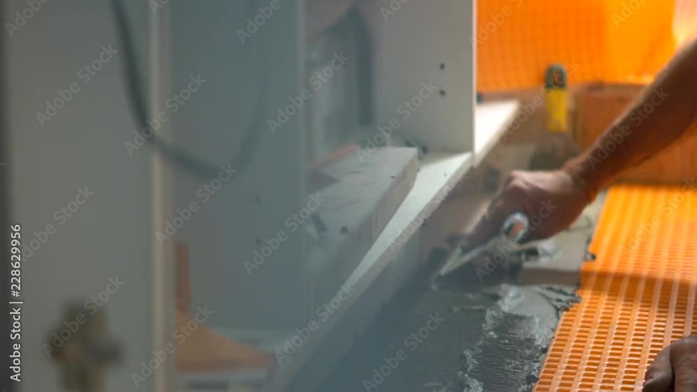 Closeup of worker spreading mortar for new ceramic floor Closeup of worker spreading mortar for new ceramic floor