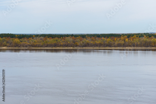 opposite bank of the Volga River with autumn forest in cloudy weather