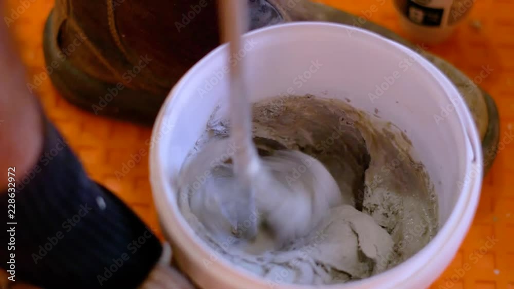Mixing mortar concrete mix to bind ceramic tiles & membrane during renovation work with an electric drill Mixing mortar concrete mix to bind ceramic tiles & membrane during renovation work with an electric drill