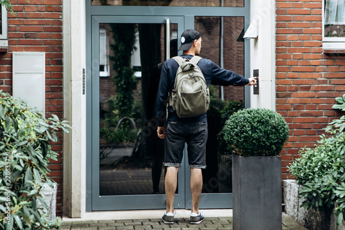 Fotografija The tourist rings the doorbell to check in to the room he has booked or the student with the backpack returns home after classes at the institute or on vacation