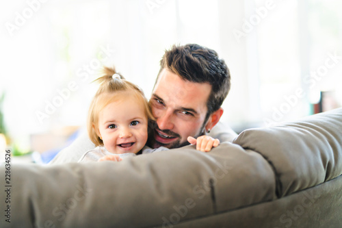 Young father with baby daughter on sofa at home