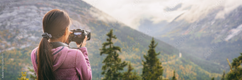 Obraz premium Travel tourist woman photographer taking pictures with video camera of nature landscape Alaska background, panoramic banner.