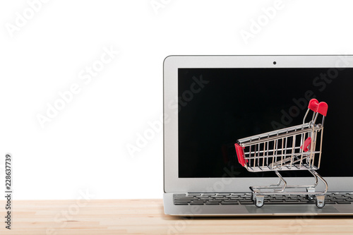Red shopping cart on a laptop isolated on white background. Online internet shopping concept. Free space for your text