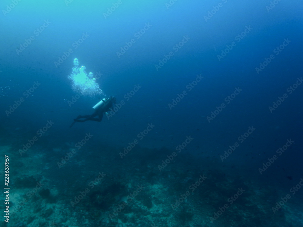 Wide shot of Scuba Diver with Air Bubbles in deep blue sea in the Waters of Bunaken Island, Diving Bunaken, Indonesia. Wide shot of Scuba Diver with Air Bubbles in deep blue sea in the Waters of Bunaken Island, Diving Bunaken, Indonesia.