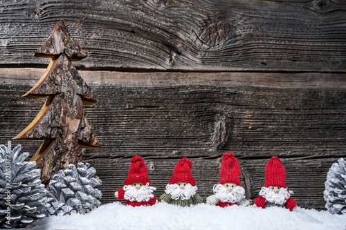 4 Weihnachtsmänner im Advent vor Holzwand