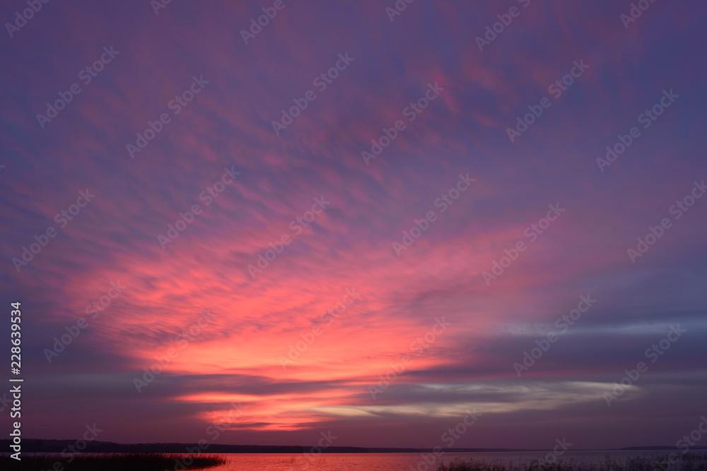 Autumn picturesque the twilight sky in the bright glowing colors of the sunset above the water surface of the lake Autumn picturesque the twilight sky in the bright glowing colors of the sunset above the water surface of the lake