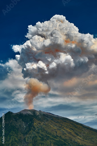 29 June 2018, Bali, Indonesia.Mount Agung volcano dramatic eruption over dark blue sky . Massive clouds of ash higlighted by magma. photo