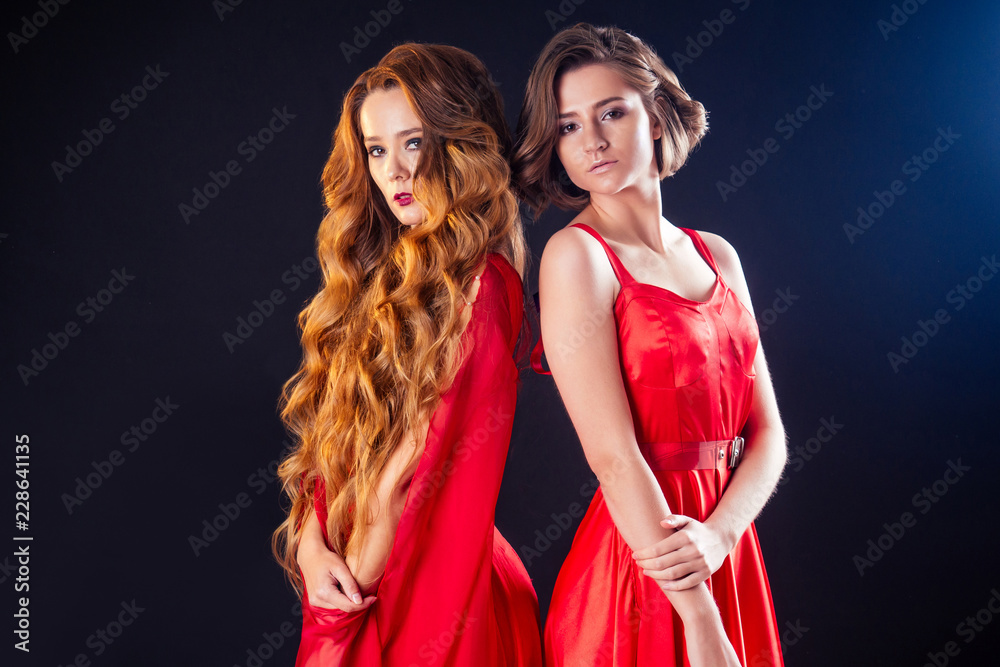 custom made wallpaper toronto digitalfashion photo of two beautiful women with luxurious long dark hair and short haircut in a red silk dress posing in studio on black background.perfect skin, professional makeup sensual model sisters