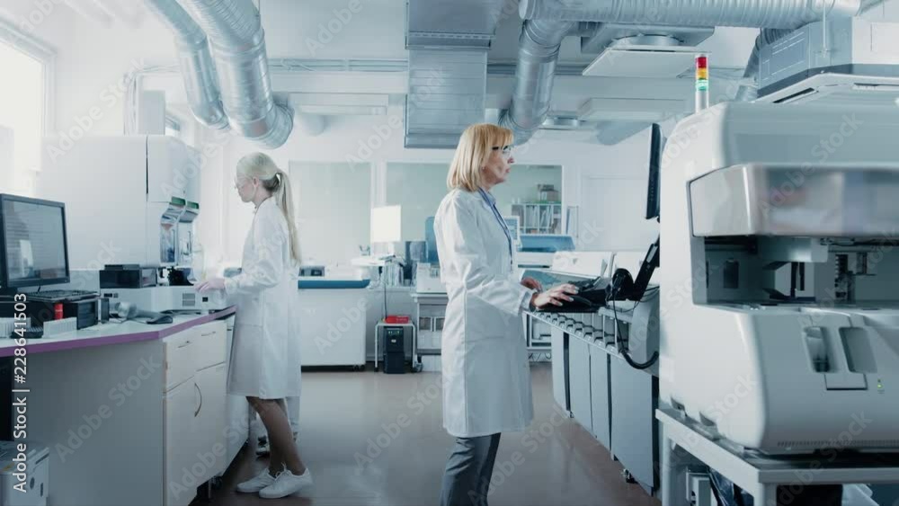 Team of Research Scientists Working On Computer, with Medical Equipment, Analyzing Blood and Genetic Material Samples with Special Machines in the Modern Laboratory.