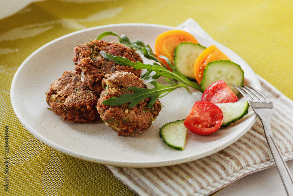 Lentils cutlet on a plate with vegetables and arugula, vegan source of protein, close-up, daylight Lentils cutlet on a plate with vegetables and arugula, vegan source of protein, close-up, daylight