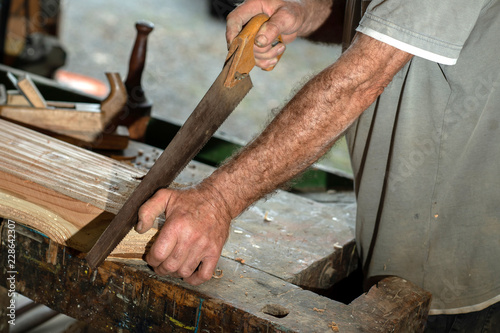 Schreiner arbeitet am Holzbalken mit Holzsäge