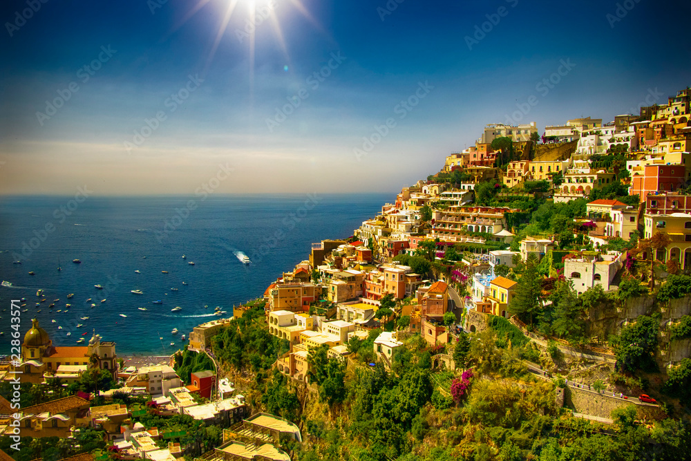 The view of Amalfi coast. This is on the south of Italy in Europe. The city stands on cliffs above the sea. There are boats on the sea. 