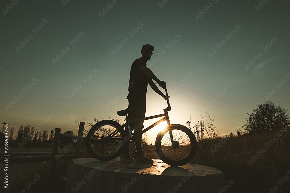 Silhouette of a guy with a bmx at sunset