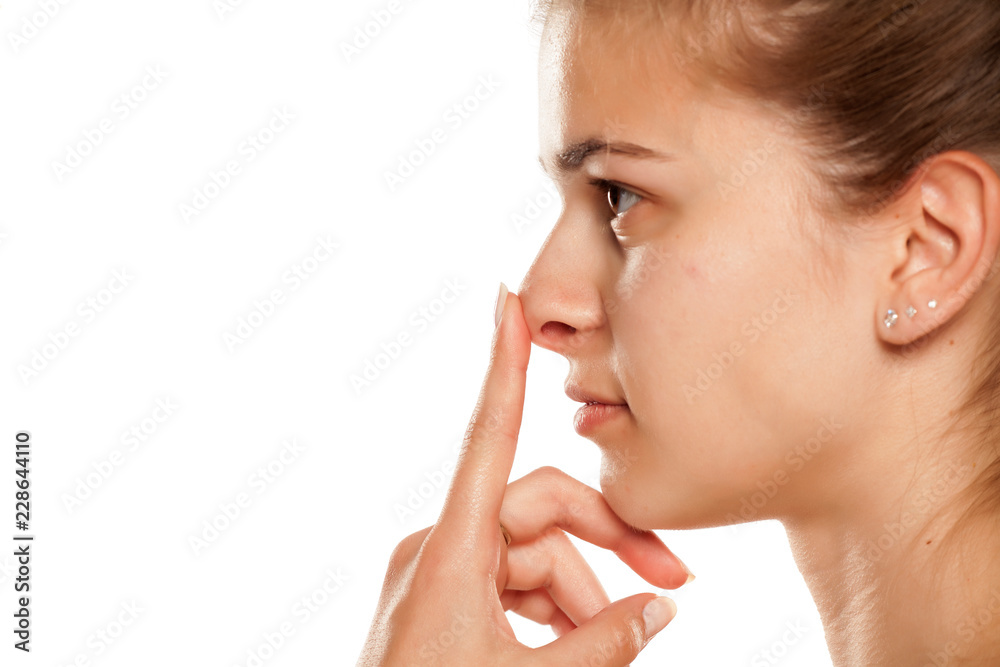 Profile of young woman touching her nose on white background Profile of young woman touching her nose on white background