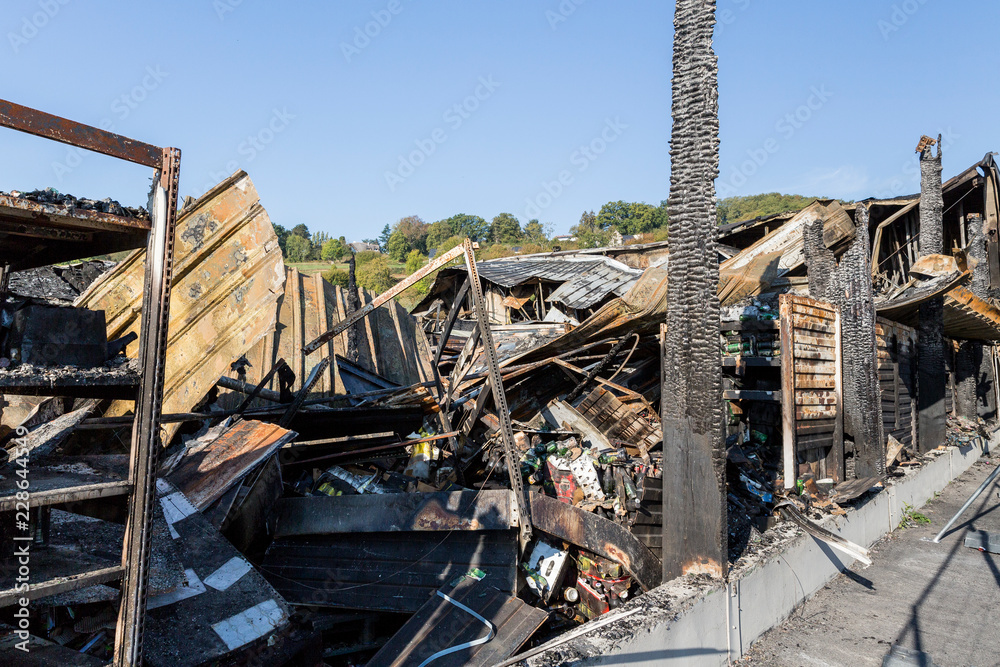 Burned damaged ruins of destroyed supermarket metallic facade arson investigation insurance