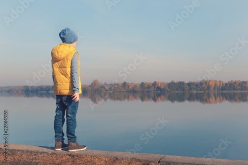 Child standing at waterfront in beautiful autumn light