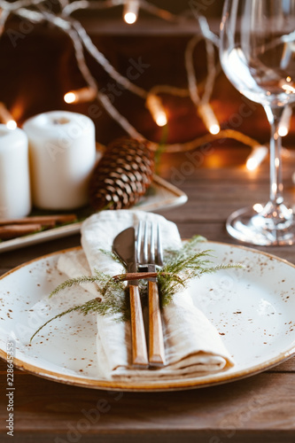 Decorated Thanksgiving or New Year table setting among white candles and winter decor. The concept of a festive dinner. photo