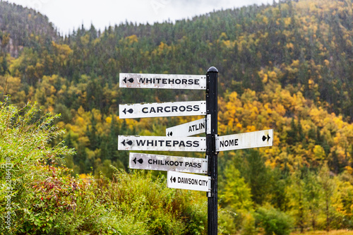 Alaska tourist street signs showing directions of different nearest tourism cities destination. Chilkoot, Whitehorse, Juneau, Skagway. Road sign in Skagway city. photo
