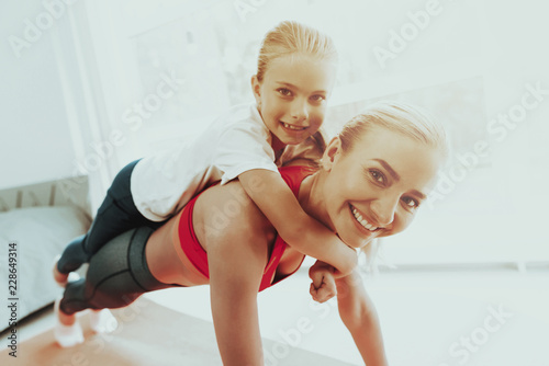 Woman Does Push Ups With Daughter On The Back.