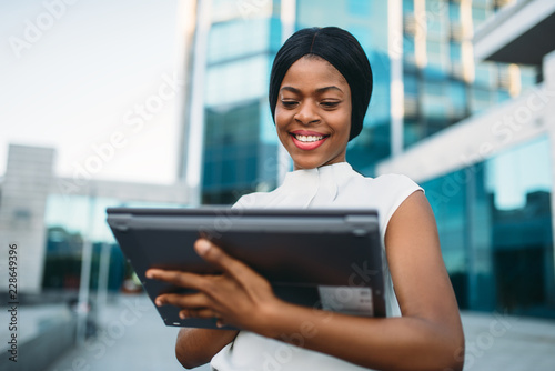 Business woman looks on laptop in front of office