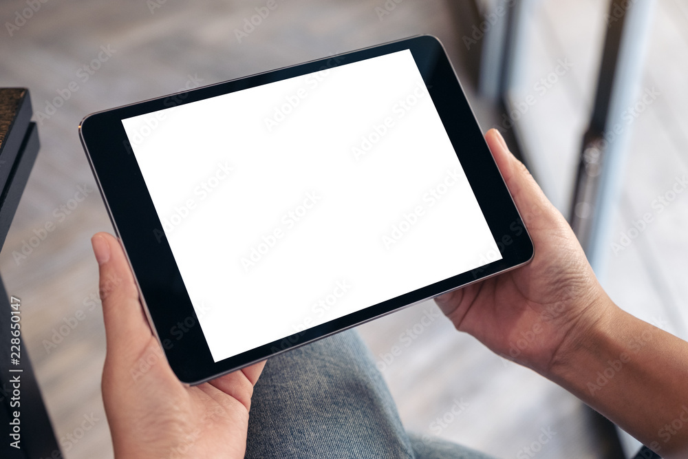 Mockup image of a woman sitting and holding black tablet pc with blank white desktop screen Mockup image of a woman sitting and holding black tablet pc with blank white desktop screen