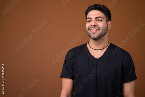 Young handsome Indian man against brown background