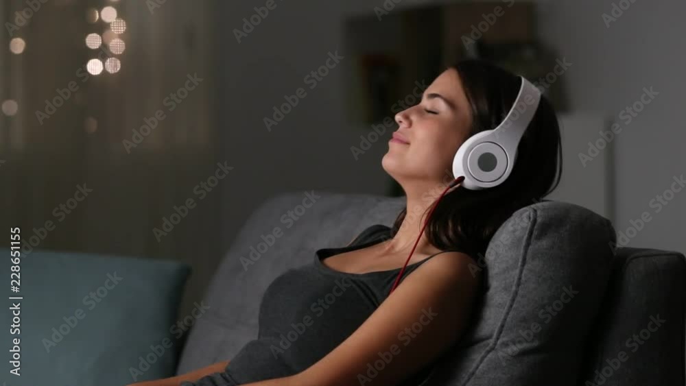Girl relaxing listening to music sitting on a couch in the night at home