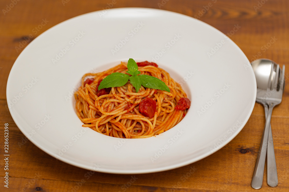Plate of delicious Italian spaghetti pasta with fresh basil leaves, with meat, tomato sauce, vegetables and grated parmesan cheese Plate of delicious Italian spaghetti pasta with fresh basil leaves, with meat, tomato sauce, vegetables and grated parmesan cheese