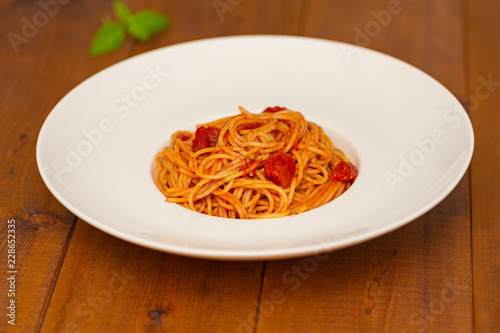 Plate of delicious Italian spaghetti pasta with fresh basil leaves, with meat, tomato sauce, vegetables and grated parmesan cheese