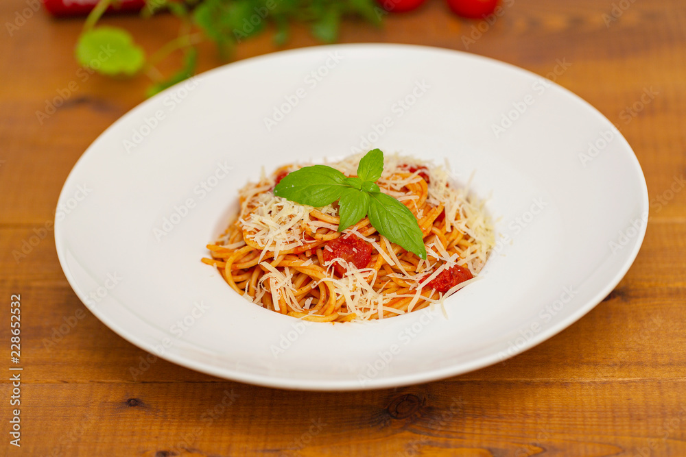Plate of delicious Italian spaghetti pasta with fresh basil leaves,  with meat, tomato sauce, vegetables and grated parmesan cheese