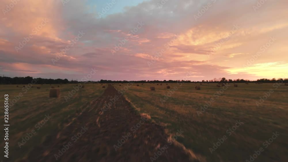 Golden multicolor sunset over a farm field with hay bales. Flying drone over a mowed wheat field at dusk. Low key 4k Golden multicolor sunset over a farm field with hay bales. Flying drone over a mowed wheat field at dusk. Low key 4k