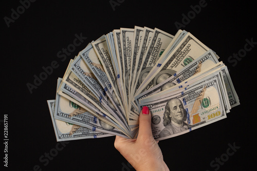 woman hand with hundred dollars bills on a black background.