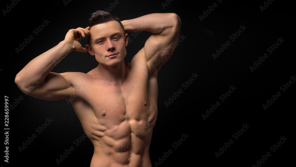 Portrait of strong healthy handsome Athletic Man Fitness Model posing near dark gray wall. Portrait of strong healthy handsome Athletic Man Fitness Model posing near dark gray wall.