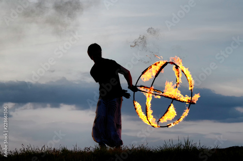 Silhouette of a fireshow performer spinning a flaming sphere