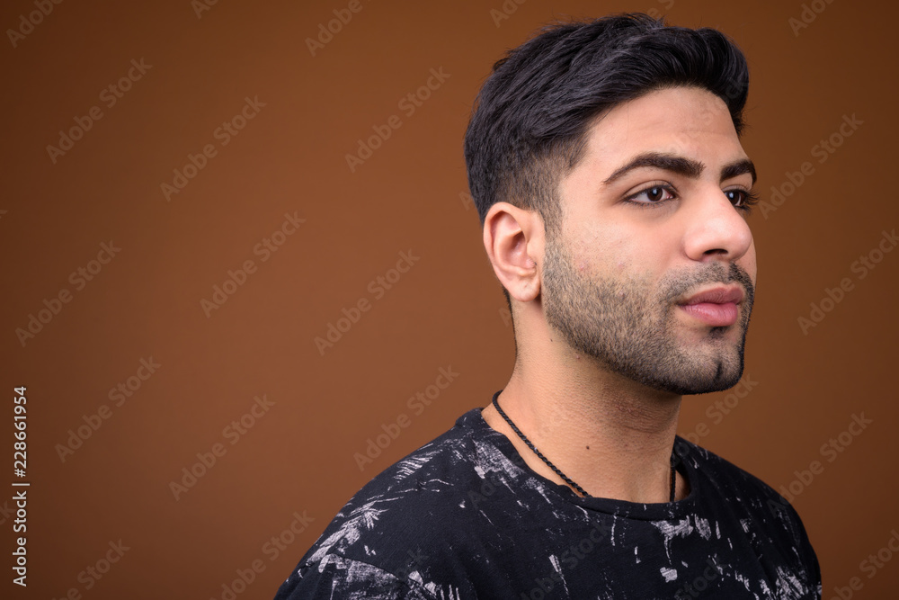 Obraz premium Young handsome Indian man against brown background