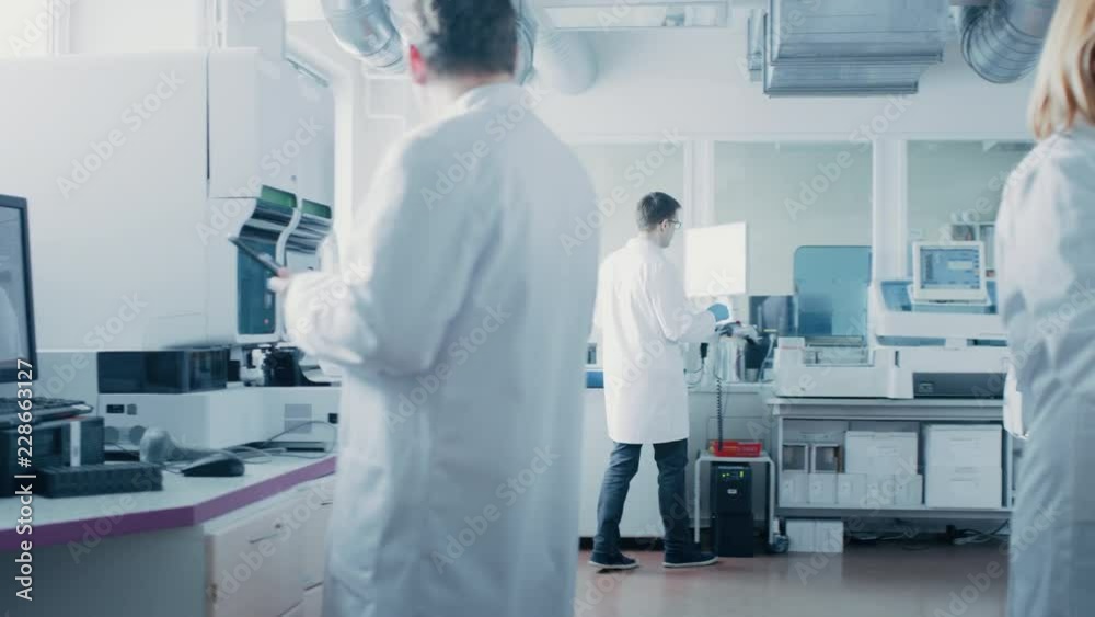 Team of Research Scientists Work in Pharmaceutical Laboratory, They Use Modern Medical Equipment, Computers, Analyze Blood and Genetic Material Samples. Team of Research Scientists Work in Pharmaceutical Laboratory, They Use Modern Medical Equipment, Computers, Analyze Blood and Genetic Material Samples.